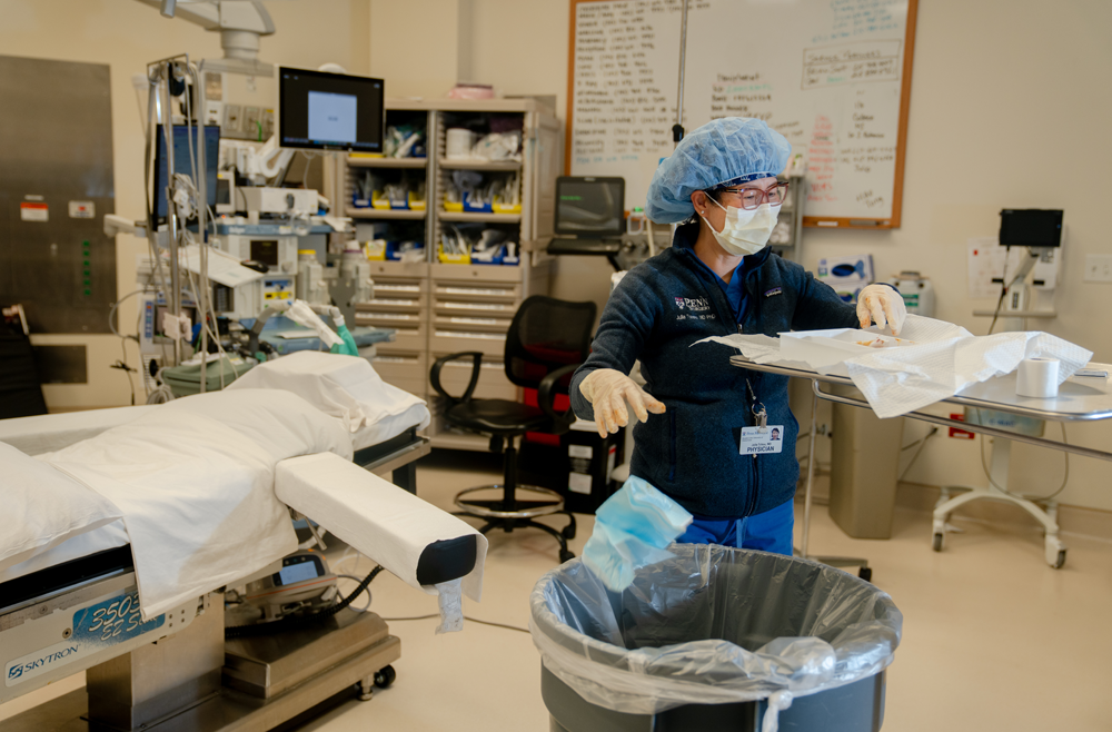 Julia Tchou, MD, PhD, throws away surgical prep kits into a trash can in an operating room